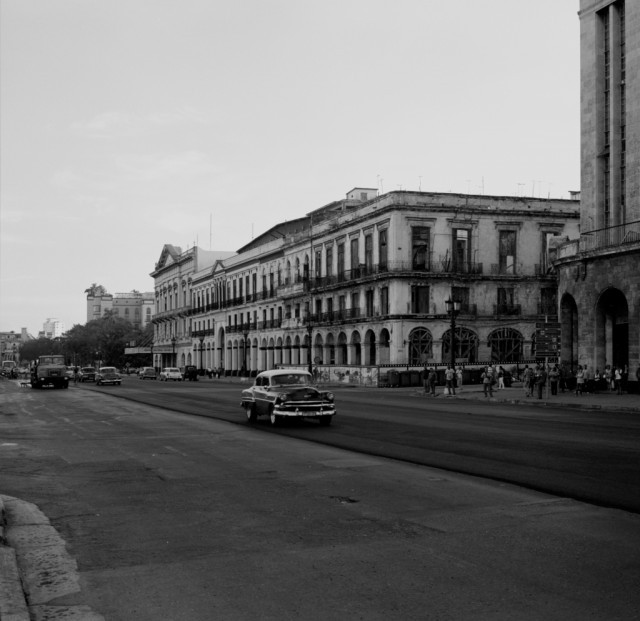 Photo: Paseo De Marti. Taken from in front of the Capitolo, looking back towards the Cine Payret. This cinema was opened in 1951 and is one of the largest in Havana. It showed the first CinemaScope film (The Robe) in 1953 (source: http://cinematreasures.org/theaters/15057). The car in the foreground is driving on new tarmac, in the background you can see a lorry spreading bitumen for the next lane.